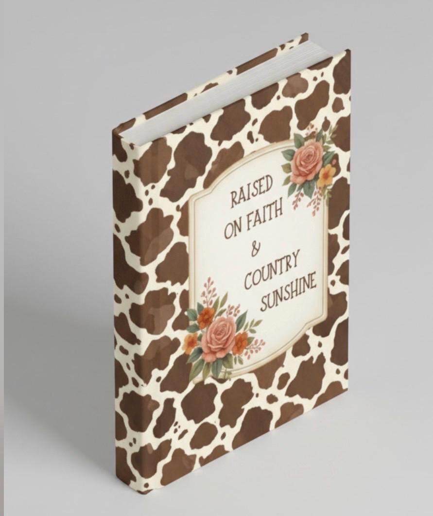 Side view of the cow print journal showing the matte hardcover binding and the thickness of the 150 lined pages.